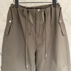Olive cargo pants close-up: elastic waistband with drawcord, front seam, and snap-button tabs