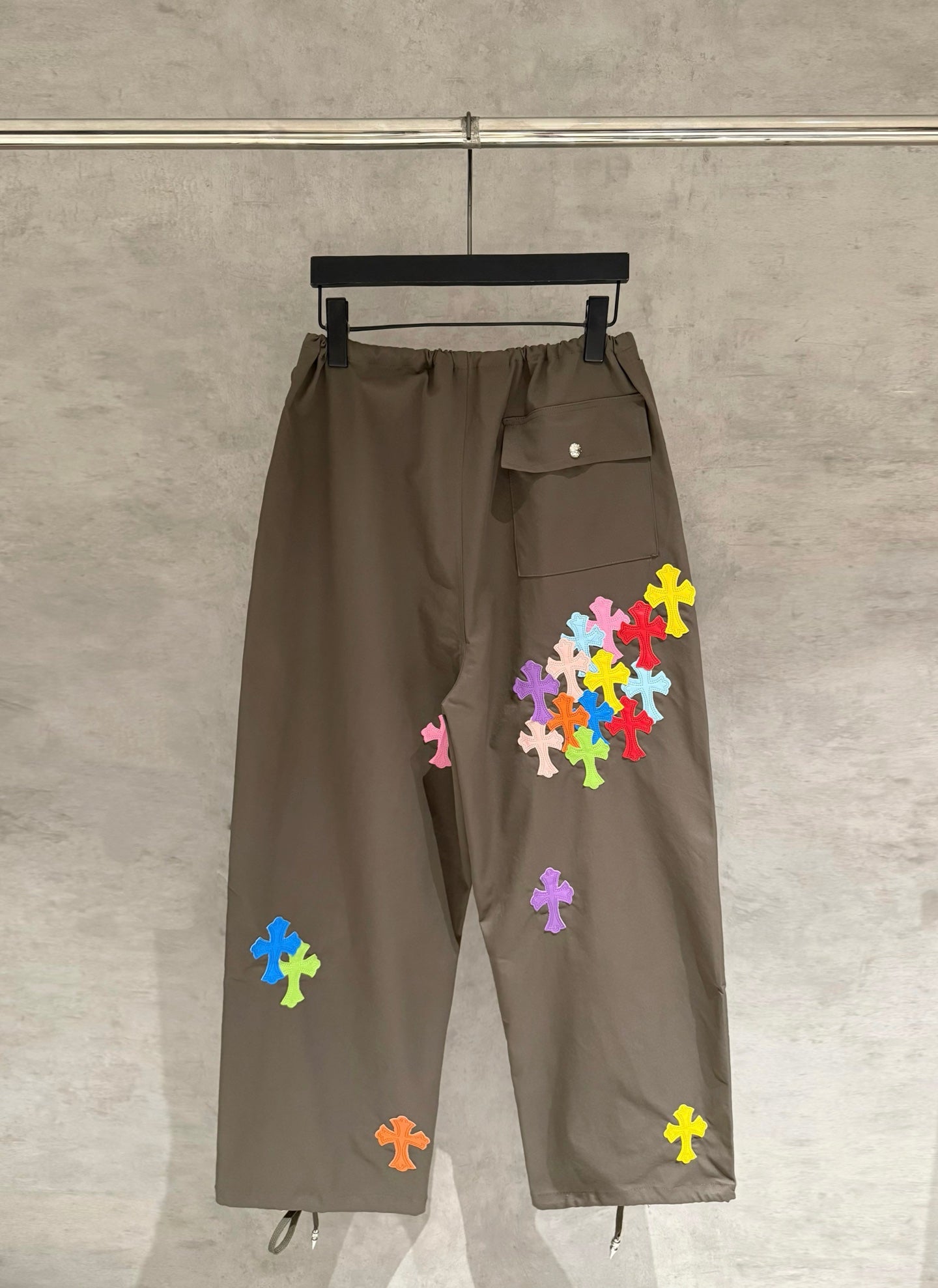 Olive cargo-style pants with elastic drawstring waist and colorful cross applique patches