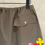 Olive cargo pants close-up: elastic waistband and snap-button back pocket