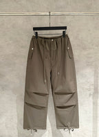 Olive cargo-style pants with elastic drawstring waist, side flap pockets, and cargo seams