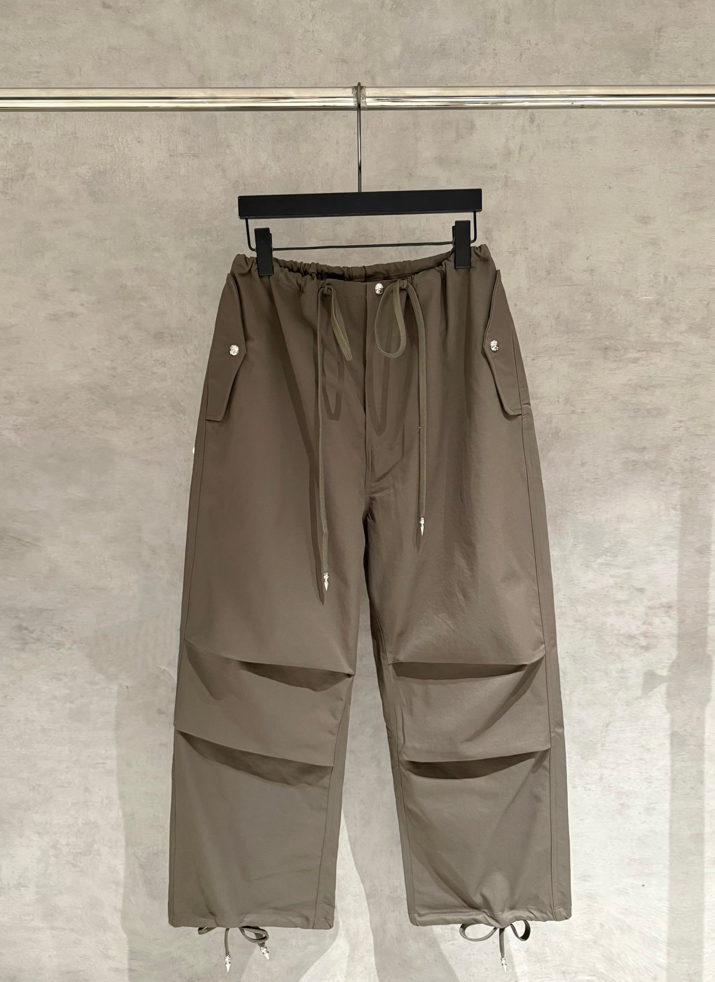 Olive cargo-style pants with elastic drawstring waist, side flap pockets, and cargo seams