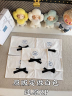 White Prada gift bags with black ribbon bows, stacked with circular logo seals