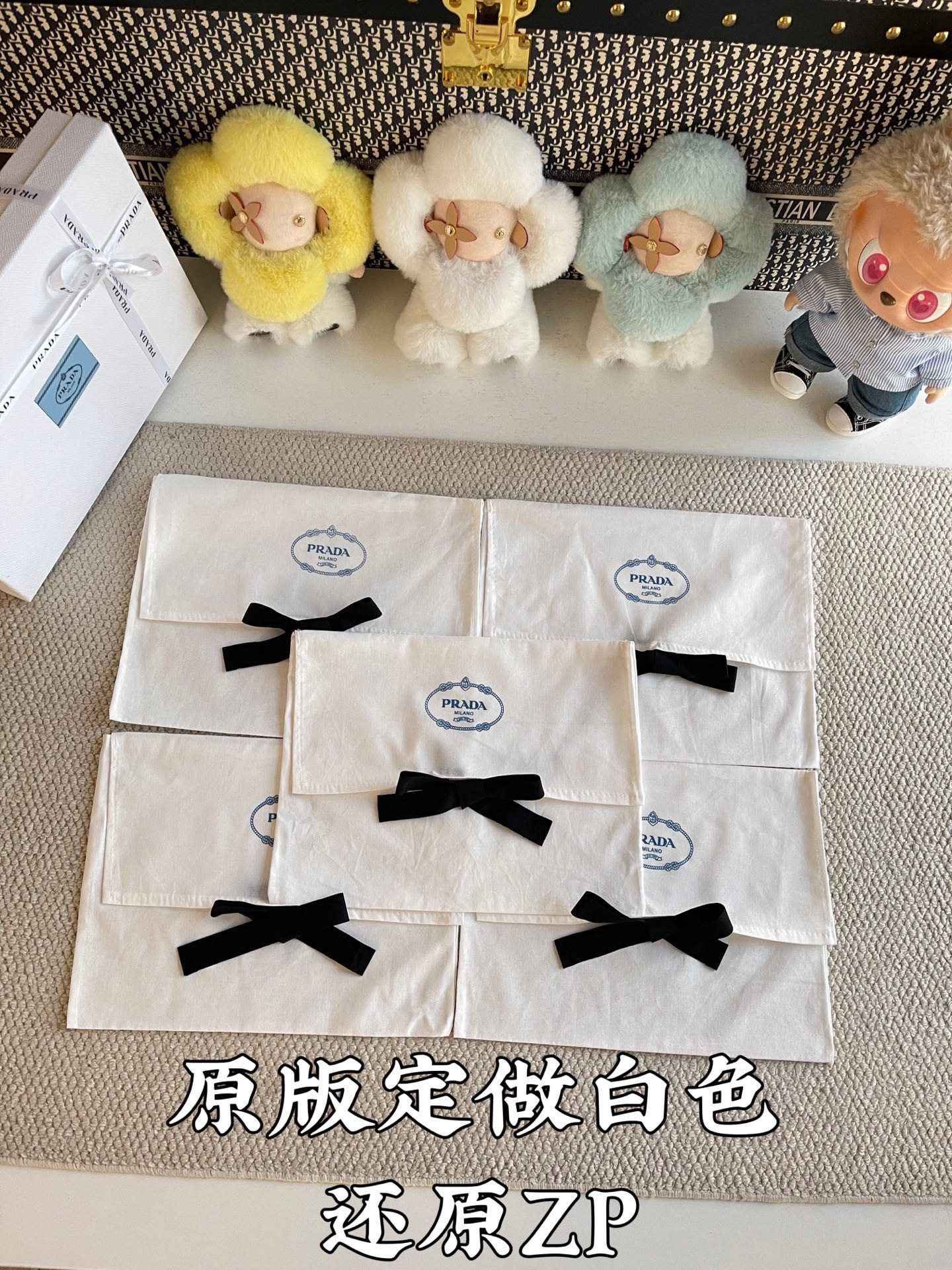 White Prada gift bags with black ribbon bows, stacked with circular logo seals