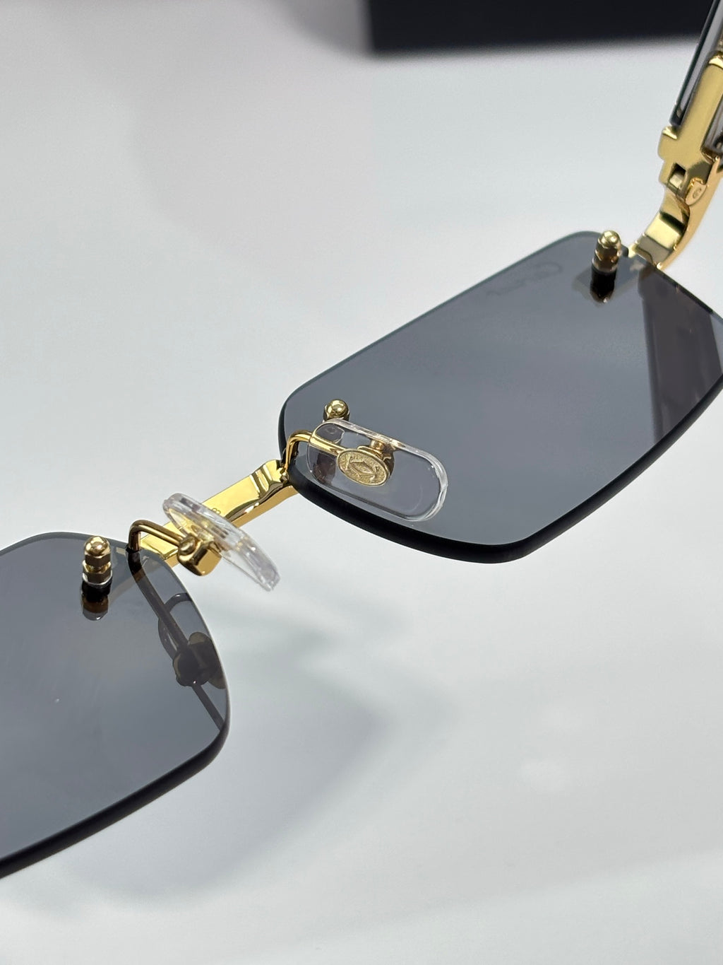 Cartier sunglasses close-up of gold temple and dark lens with clear nose pads