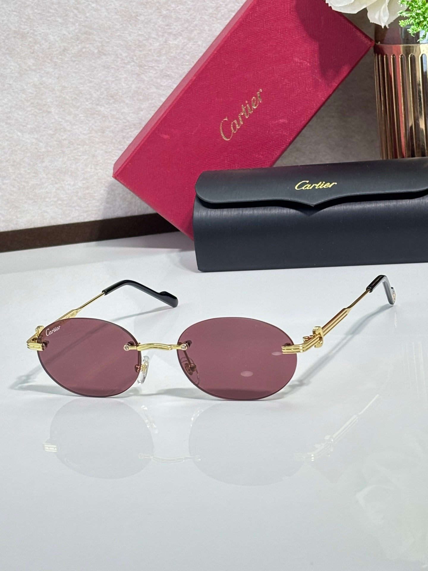 Round rose-pink sunglasses with gold-tone metal frame and dark temple tips