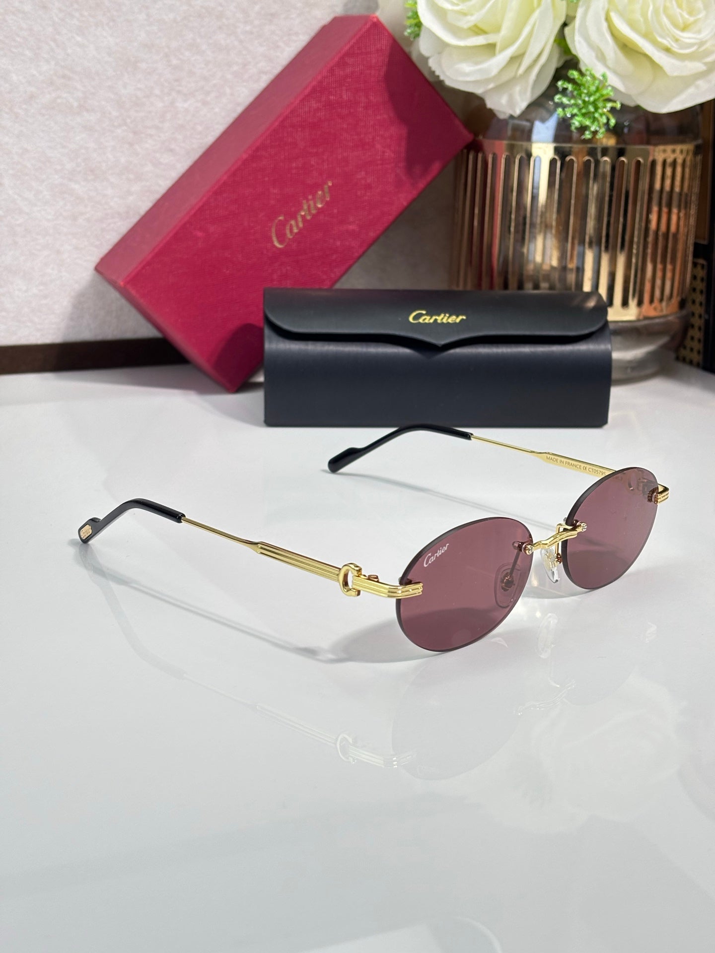 Round rose-pink sunglasses with gold-tone metal frame and thin arms with gold detail