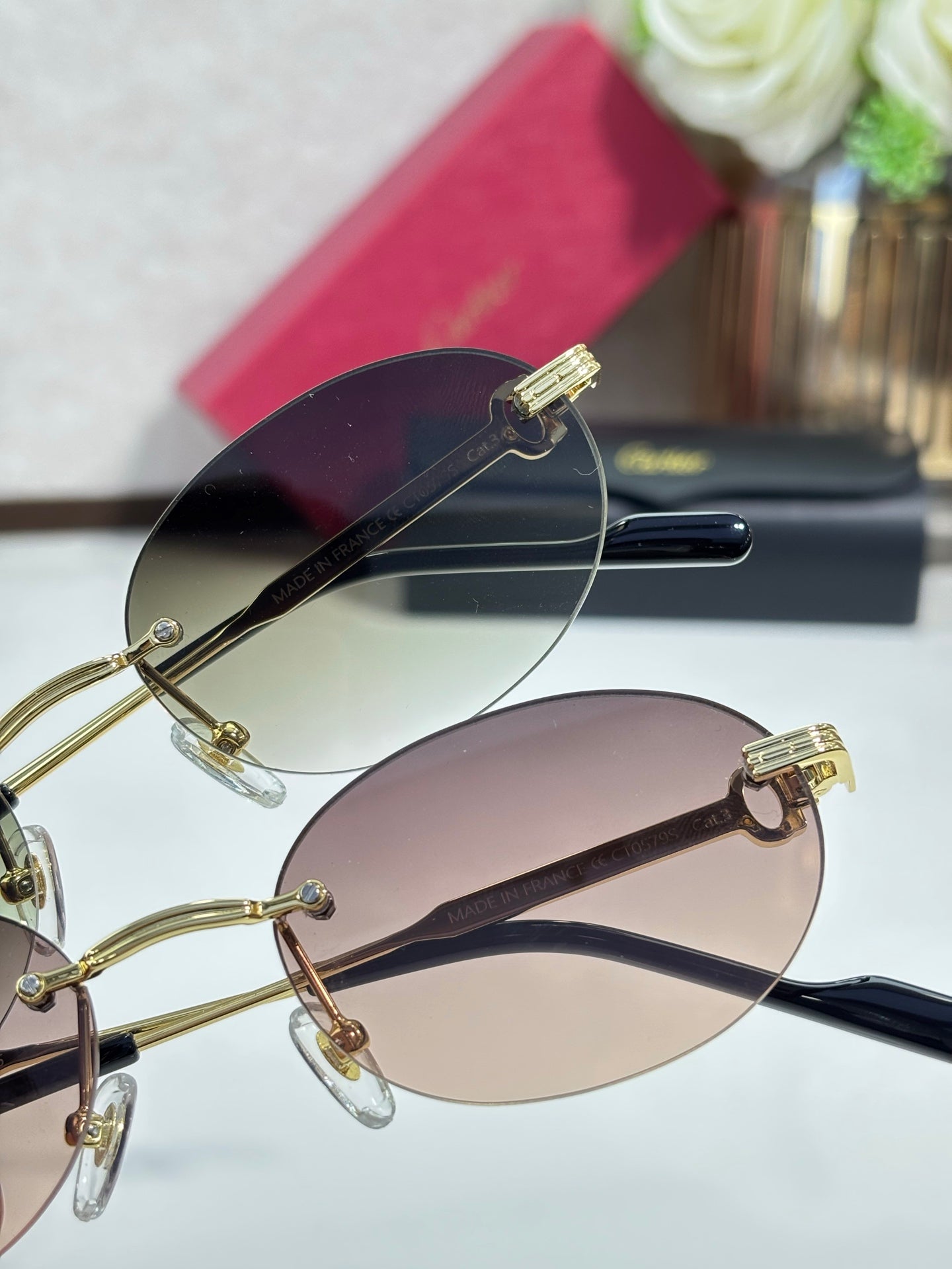 Round rose-tinted sunglasses with gold-tone metal frame and dark temple arms