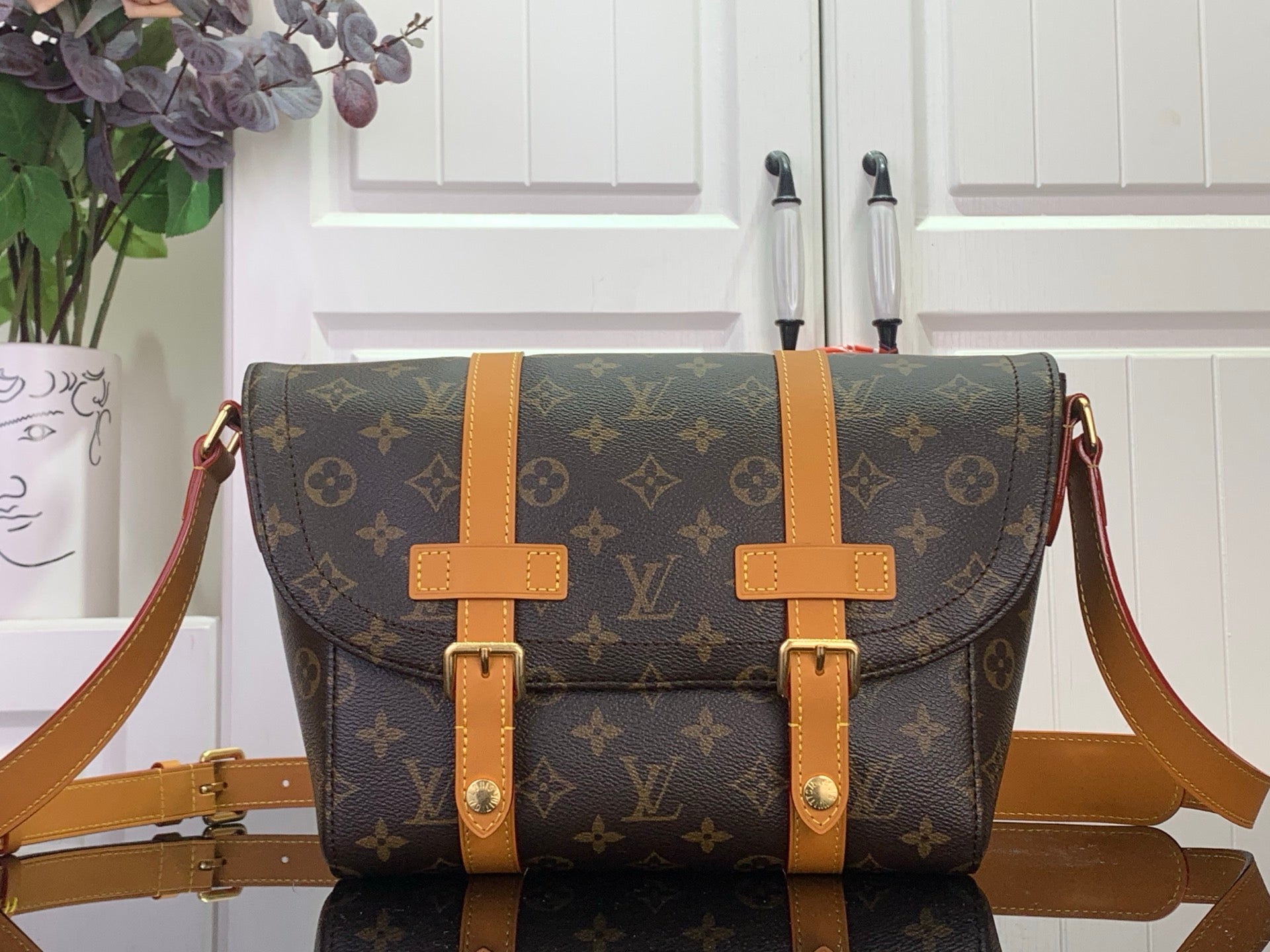 Louis Vuitton monogram bag with tan leather straps and buckles, crossbody style