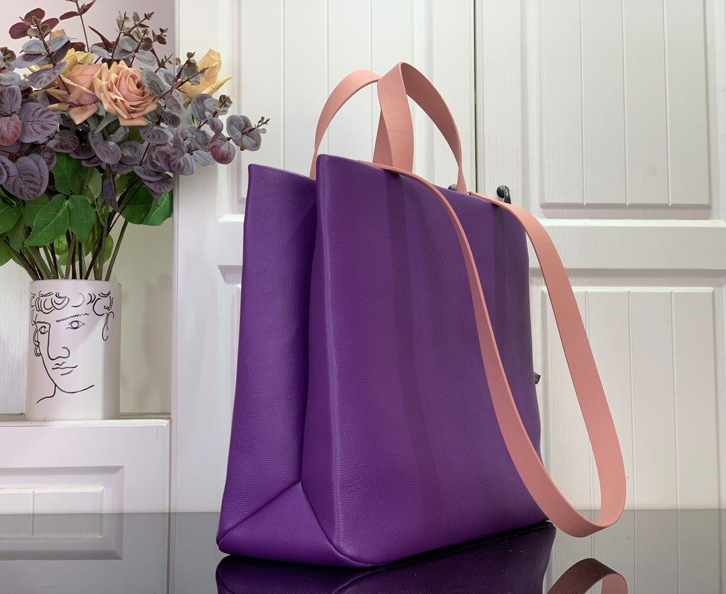 Purple tote bag angled view with tan shoulder strap and handles