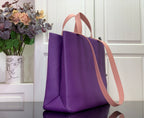 Purple tote bag angled view with tan shoulder strap and handles