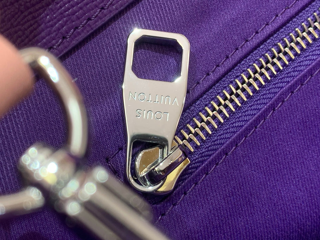 Silver zipper pull and Noé signature tag on purple bag