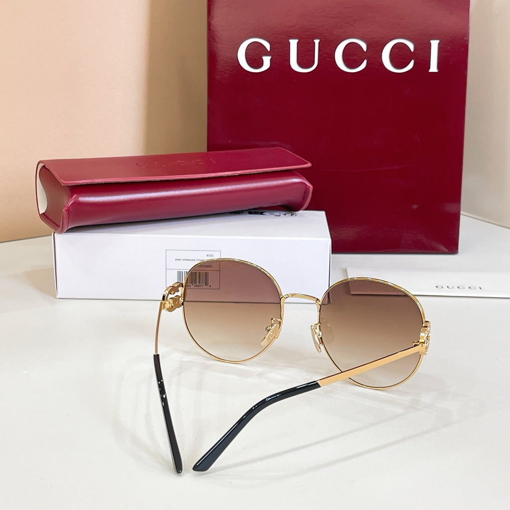 Round sunglasses with gold-tone frame and rose tinted lenses, black metal temples.