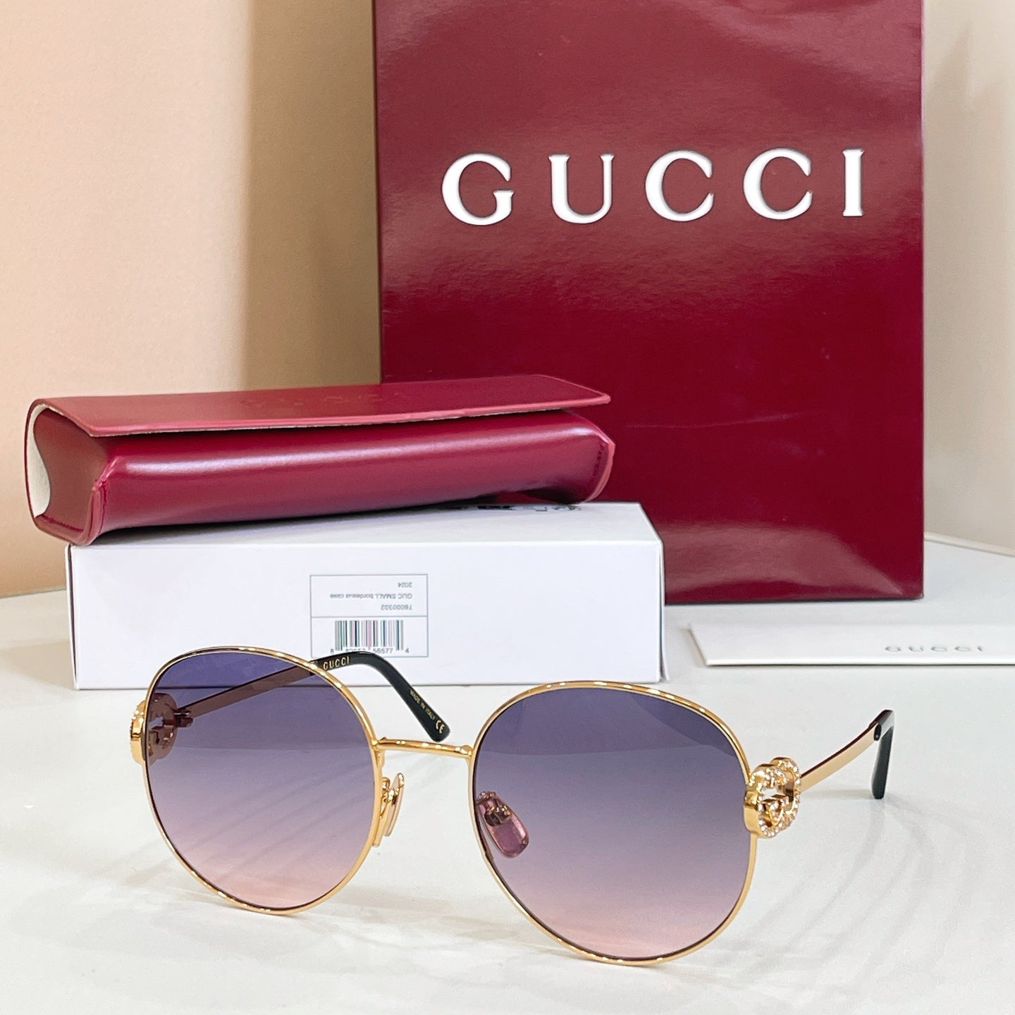 Round sunglasses with gold-tone frame and purple tinted lenses, slim metal arms.