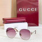 Round sunglasses with silver-tone frame and purple tinted lenses, curved metal temples.