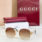 Round sunglasses with gold-tone frame and light brown tinted lenses, black temple tips.
