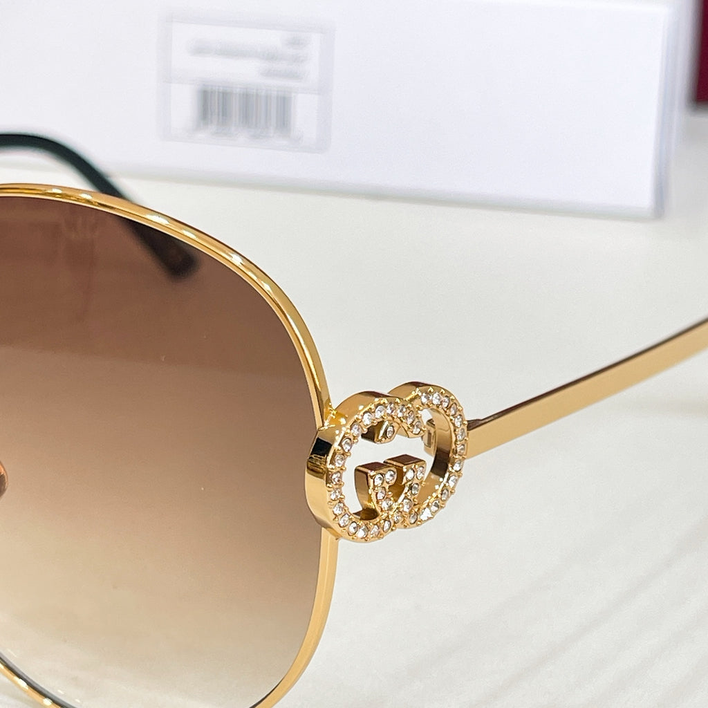 Gold-tone round sunglasses with crystal-like emblem on the frame bridge.