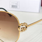 Gold-tone round sunglasses with crystal-like emblem on the frame bridge.