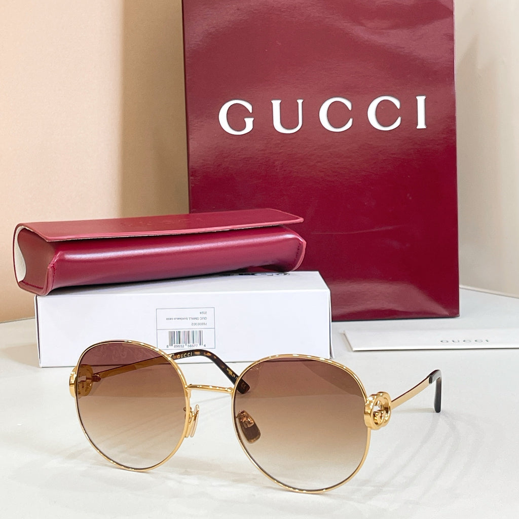 Round sunglasses with gold-tone frame and amber tinted lenses, thin metal arms.