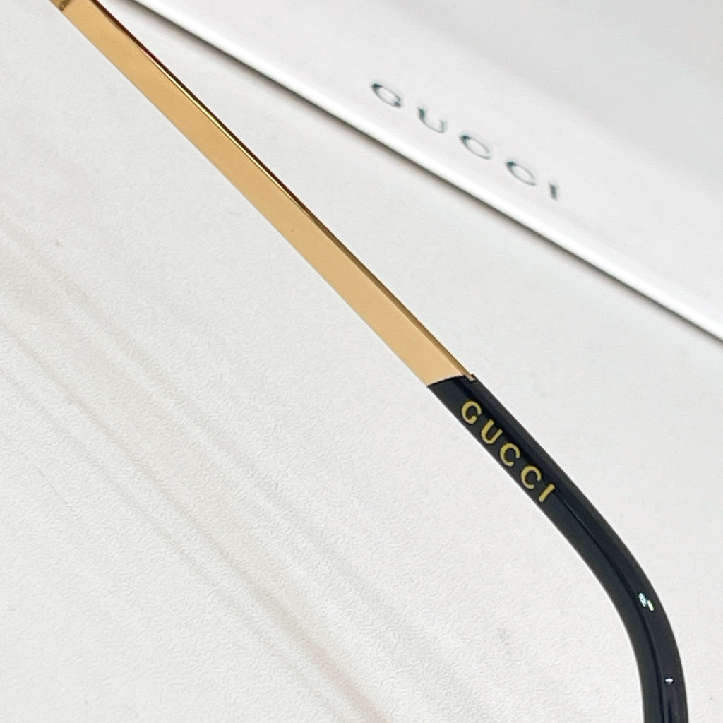 Gold and black sunglasses temple with Gucci lettering near the arm