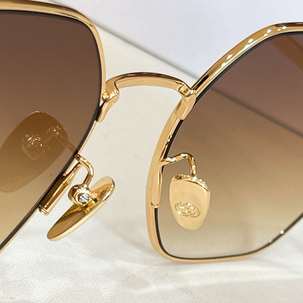 Gold sunglasses with hinged detail and amber tinted lenses