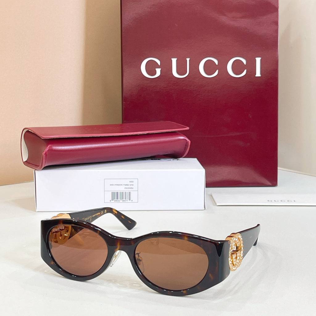 Gucci sunglasses with black frames and warm brown lenses, gold emblem on temple