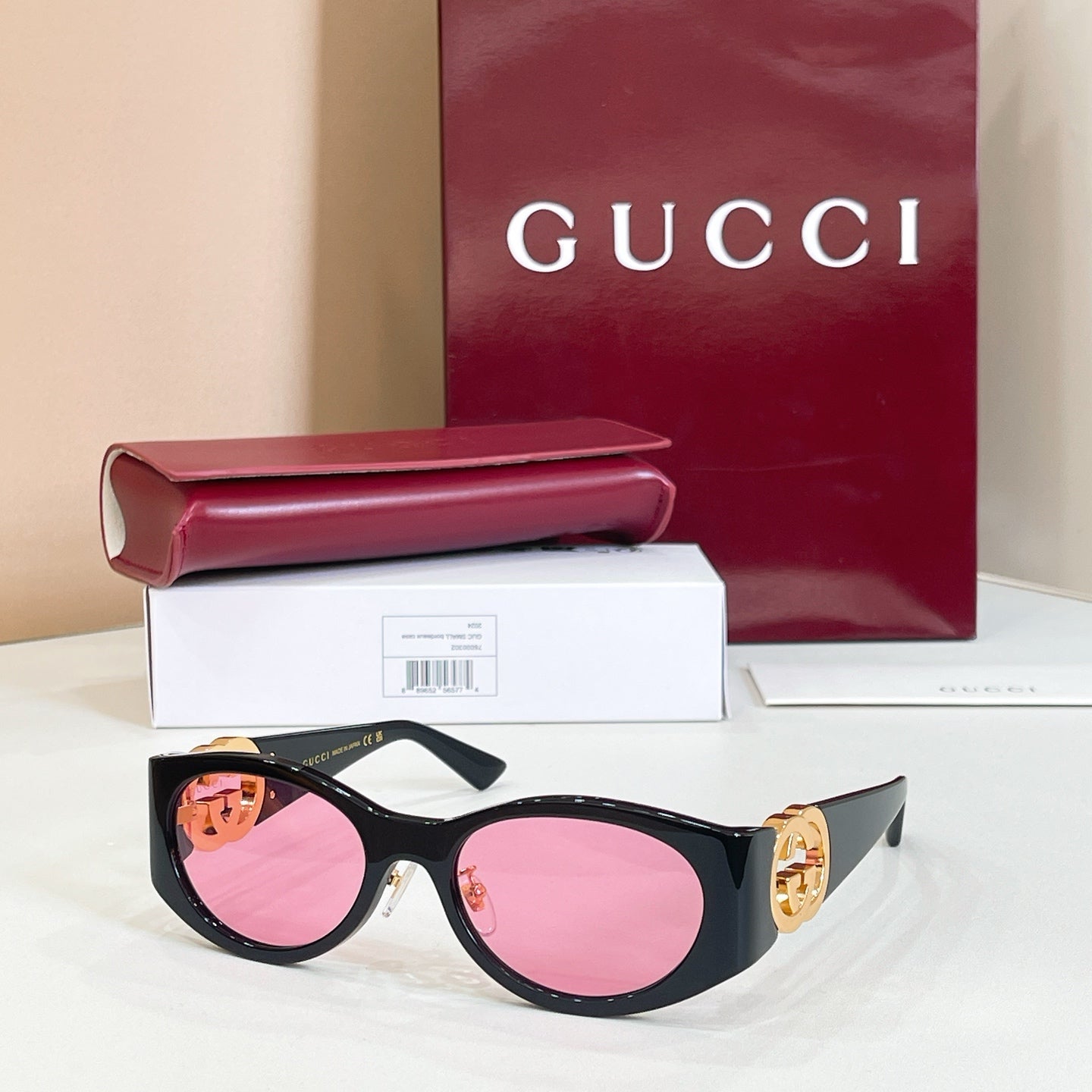 Gucci sunglasses with black frames and pink lenses, gold logo on temple