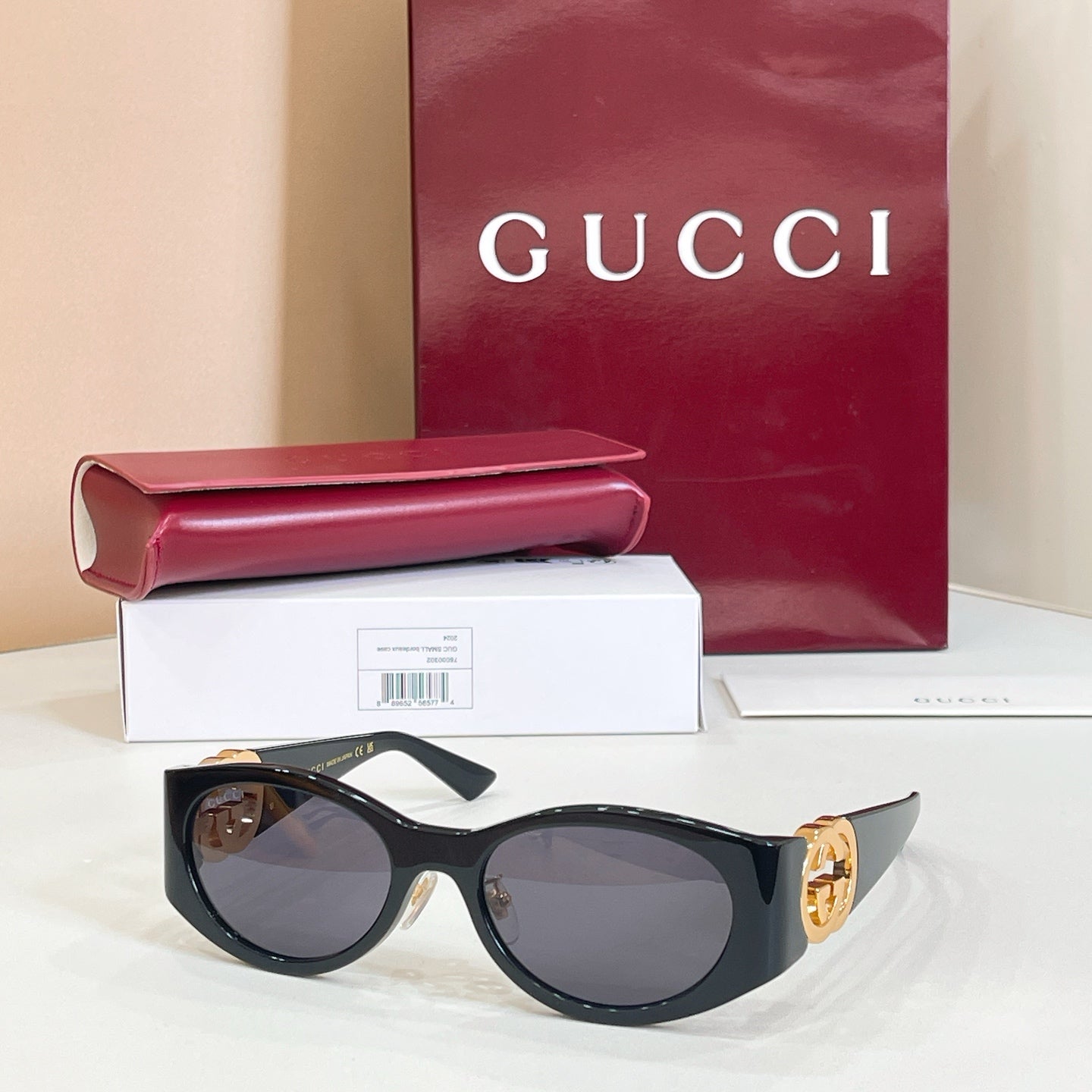 Gucci sunglasses with black frames and dark gray lenses, gold logo on temple
