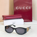 Gucci sunglasses with dark lenses and black frame, gold logo accent on temple