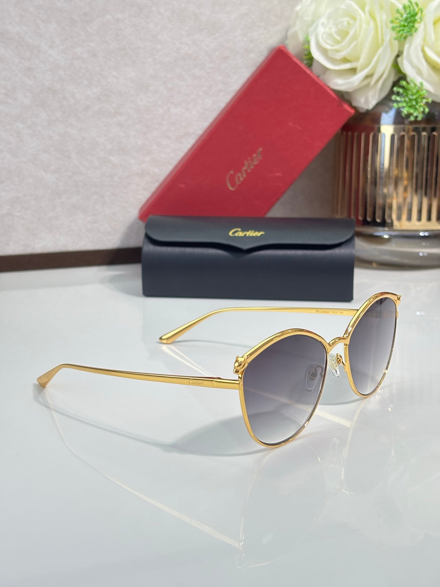 Gold round sunglasses with tinted gray lenses and slim metal frame, with protective case.