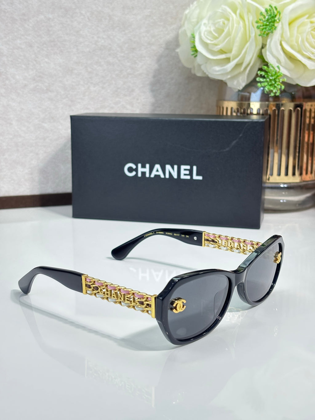 Black sunglasses with dark lenses and gold chain temples with CC