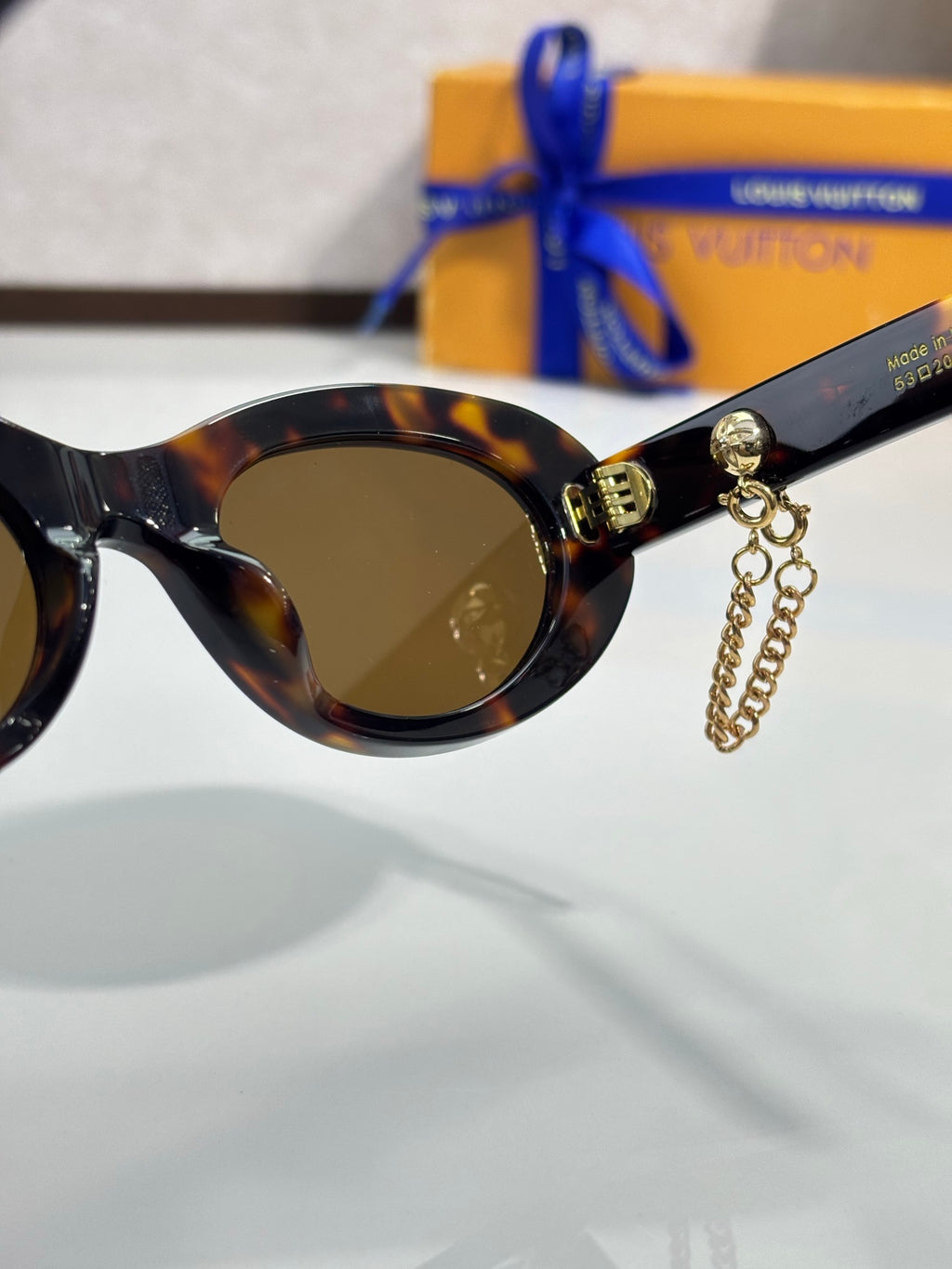 Louis Vuitton tortoise sunglasses close-up with tinted lens and gold chain charm
