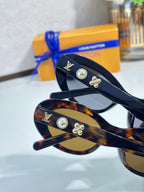 Louis Vuitton tortoise cat-eye sunglasses with gold logo studs and tinted lenses