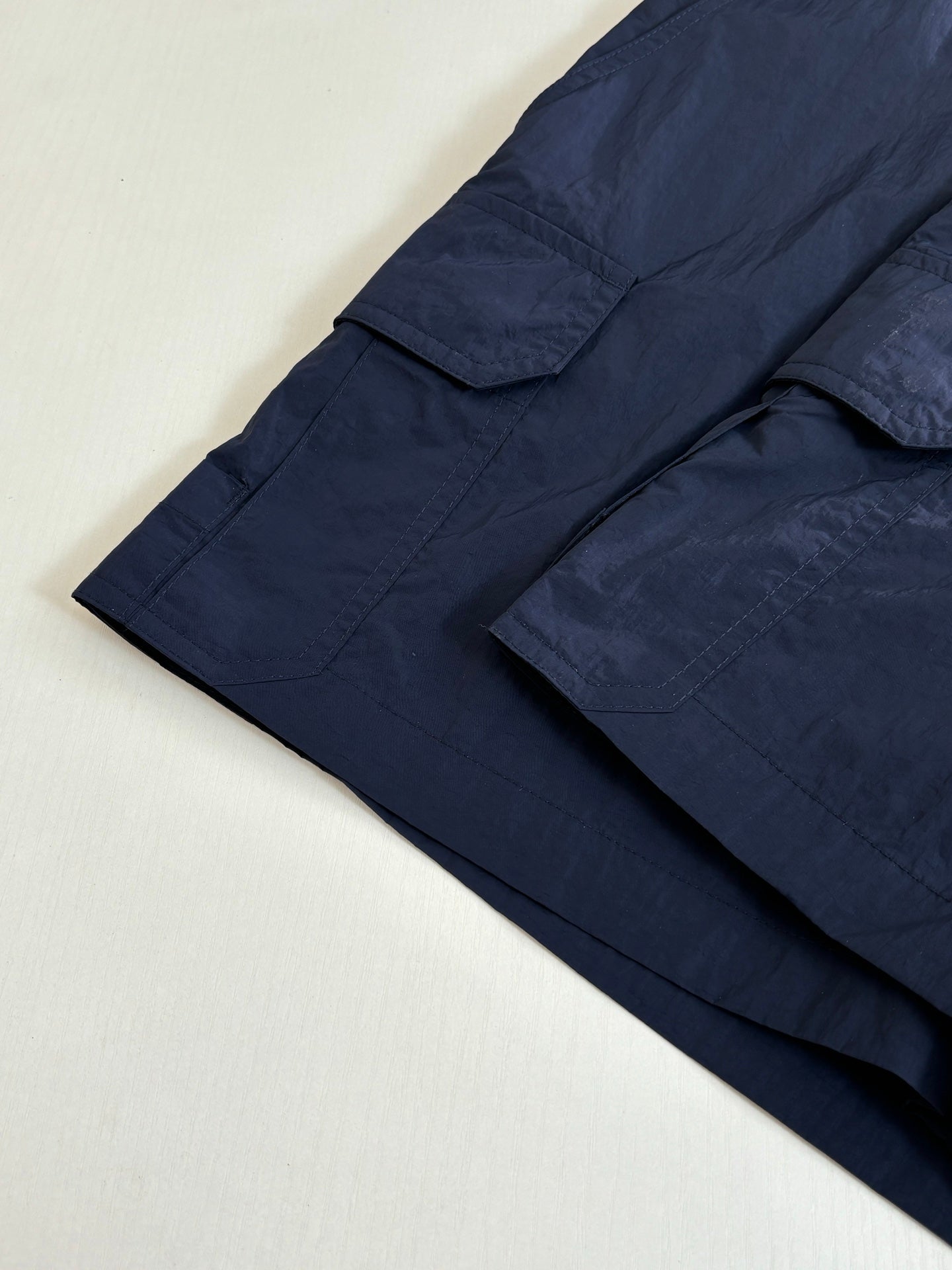 Navy cargo shorts with layered hem and stitched creases