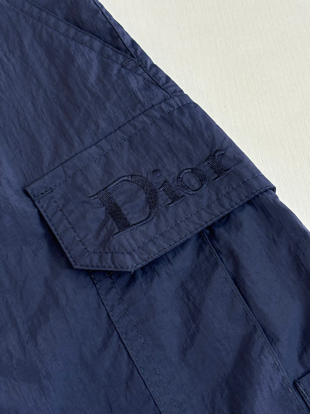 Navy cargo shorts with stitched logo patch on pocket