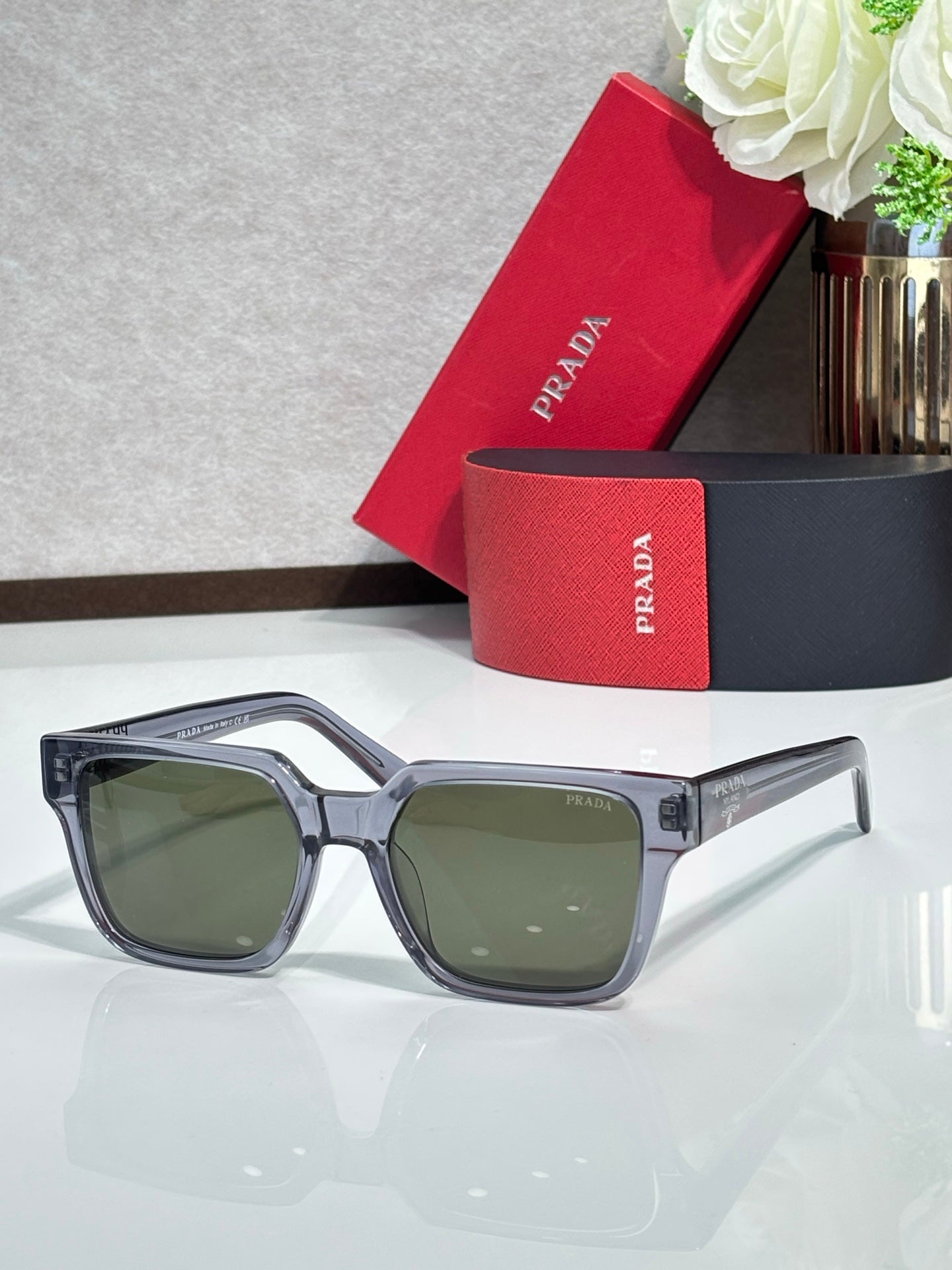 Prada sunglasses with light gray frame and green-tinted lenses