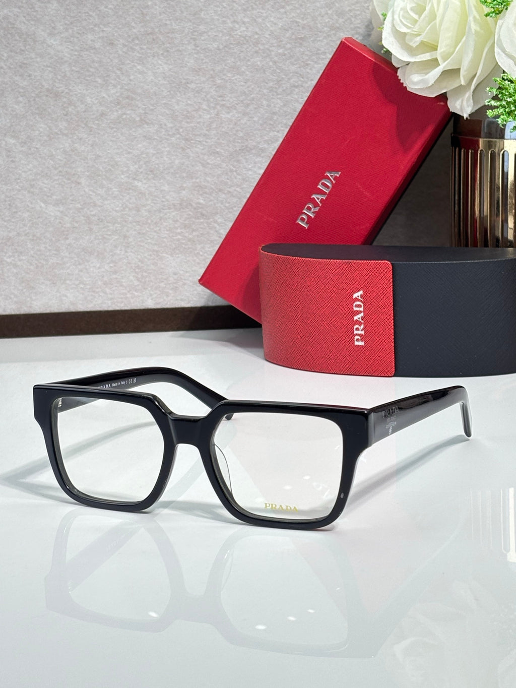 Black rectangular eyeglasses with clear lenses and logo on temple