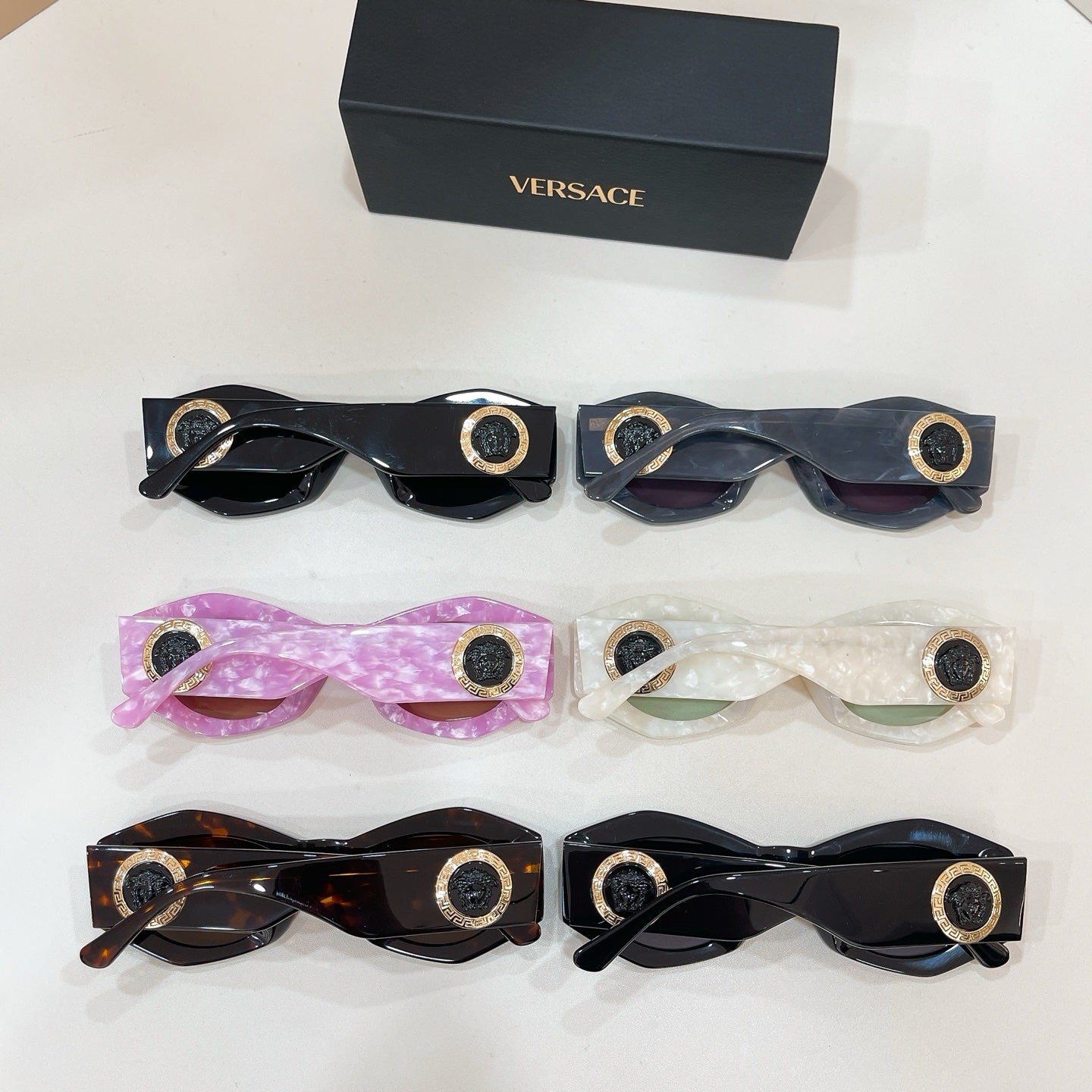 Assorted sunglasses set with gold logo medallion details in black, pink, and tortoiseshell
