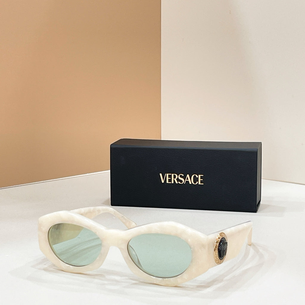 White cat-eye sunglasses with light blue lenses and gold logo detail on the temple