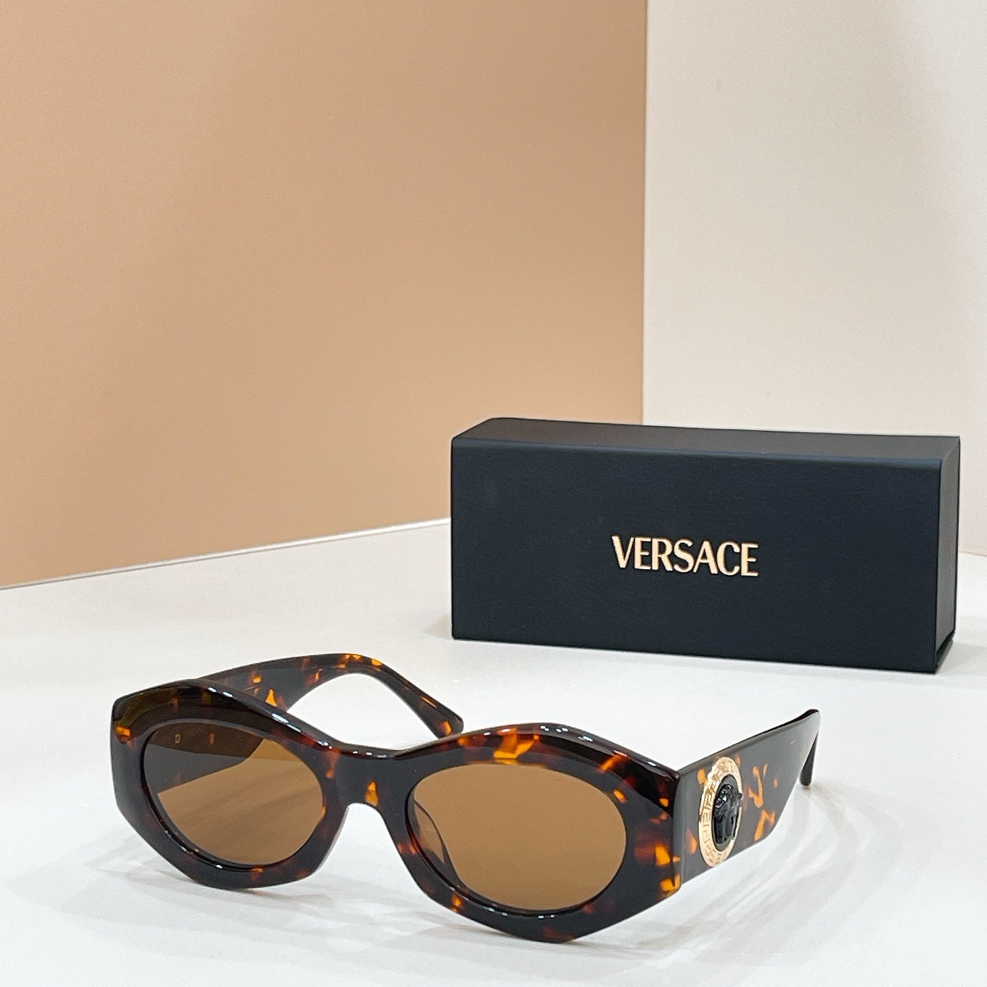 Tortoiseshell sunglasses with brown-tinted lenses and gold logo medallion on the temple