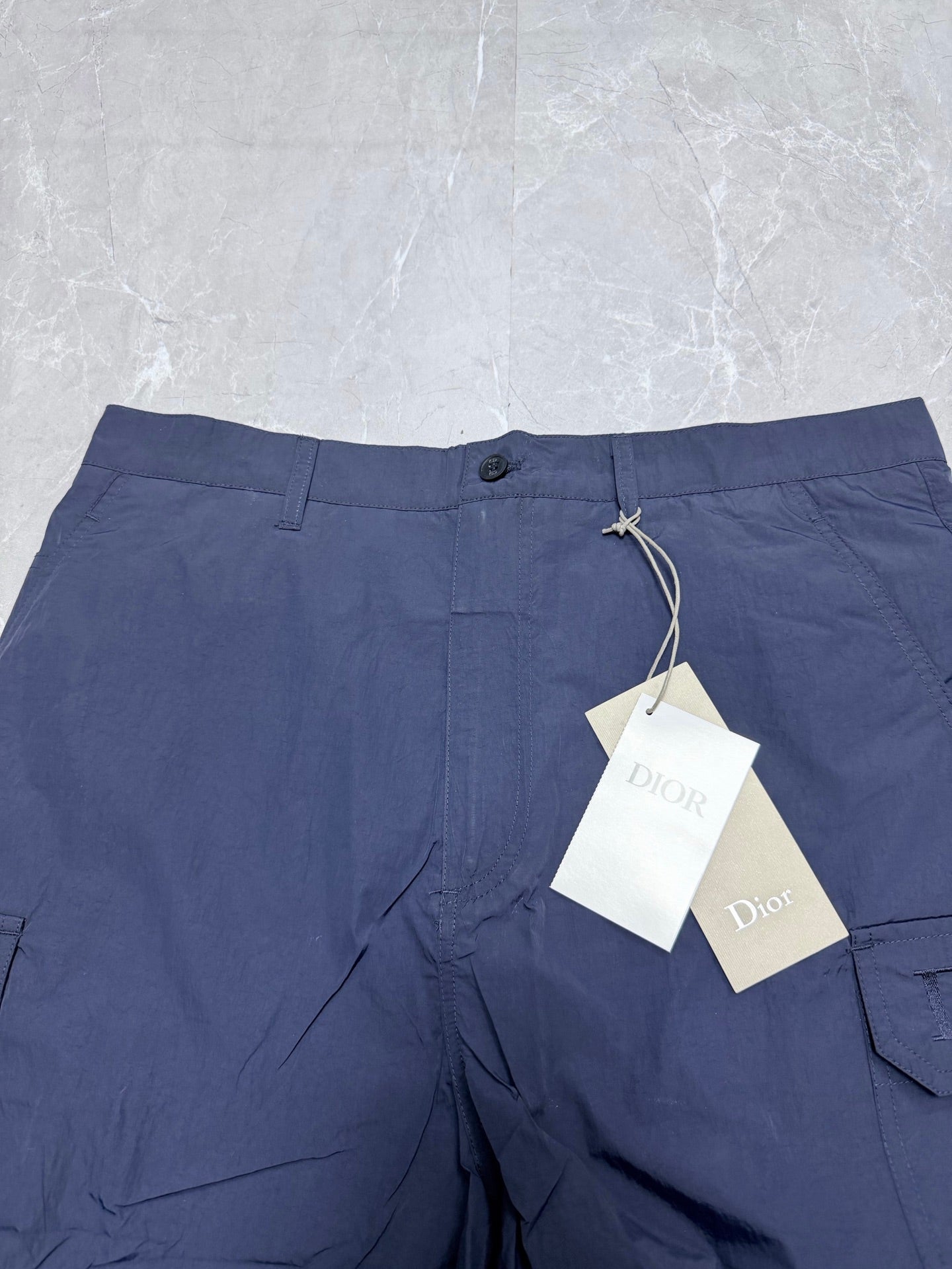 Navy Dior shorts waistband with button closure and hanging tags