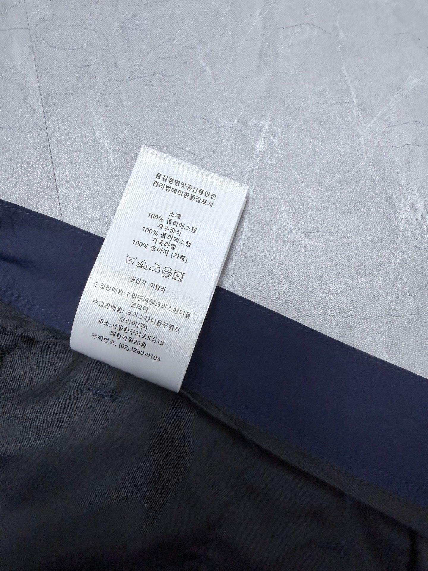 Dior navy shorts leg with overlapping care label and printed instructions