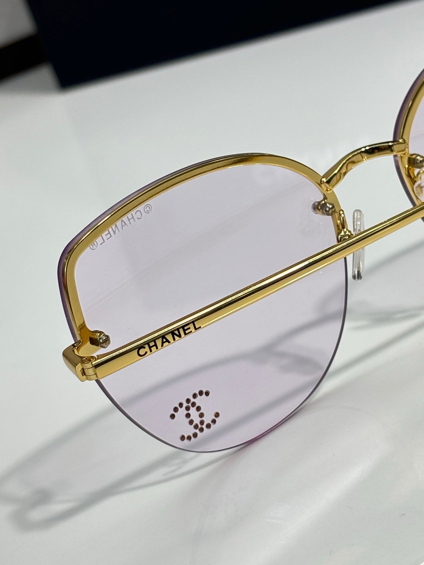 Chanel sunglasses close-up: gold oval frame with purple lens tint