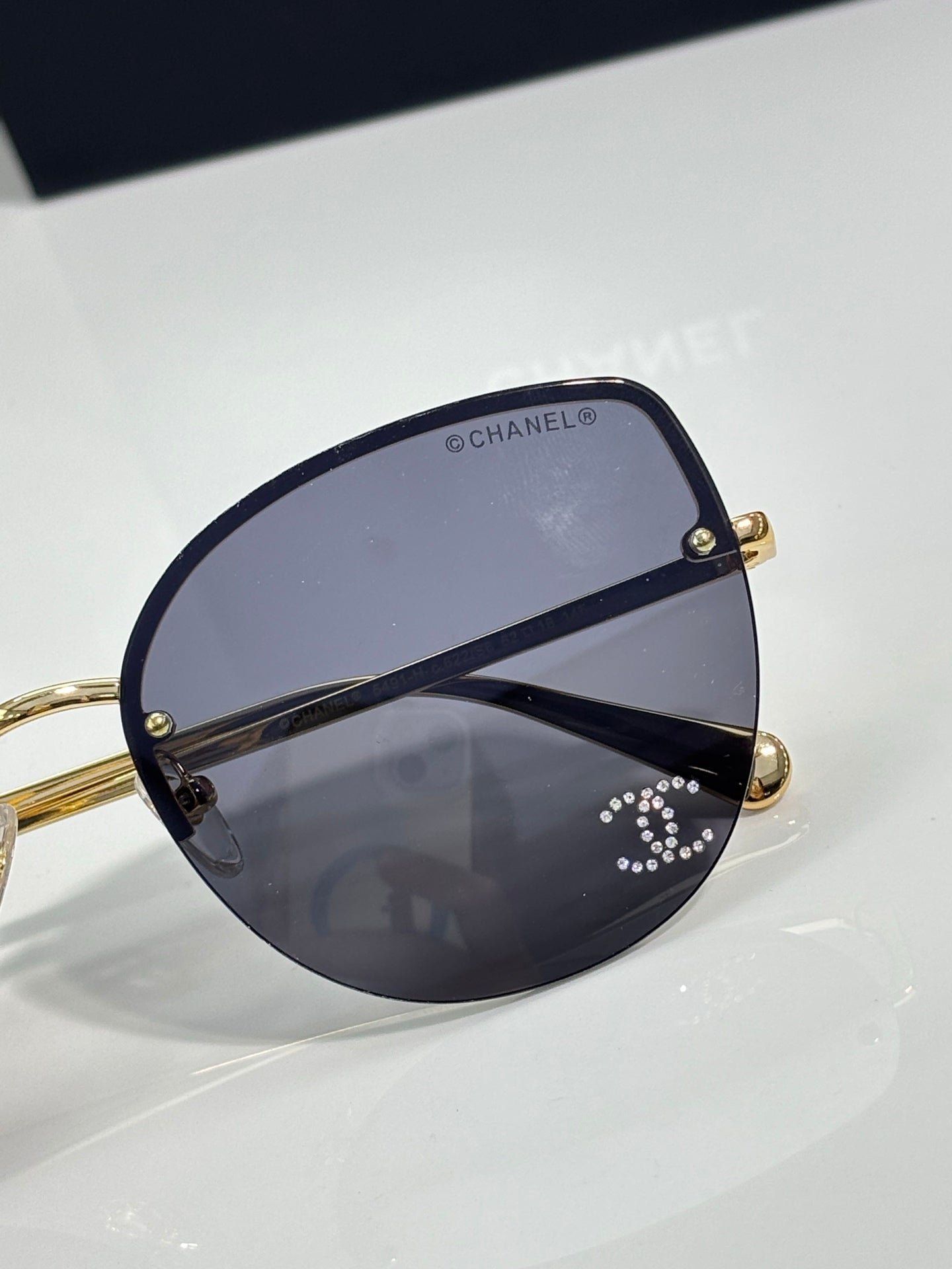 Chanel sunglasses close-up: gold hinges with dark blue gradient lens