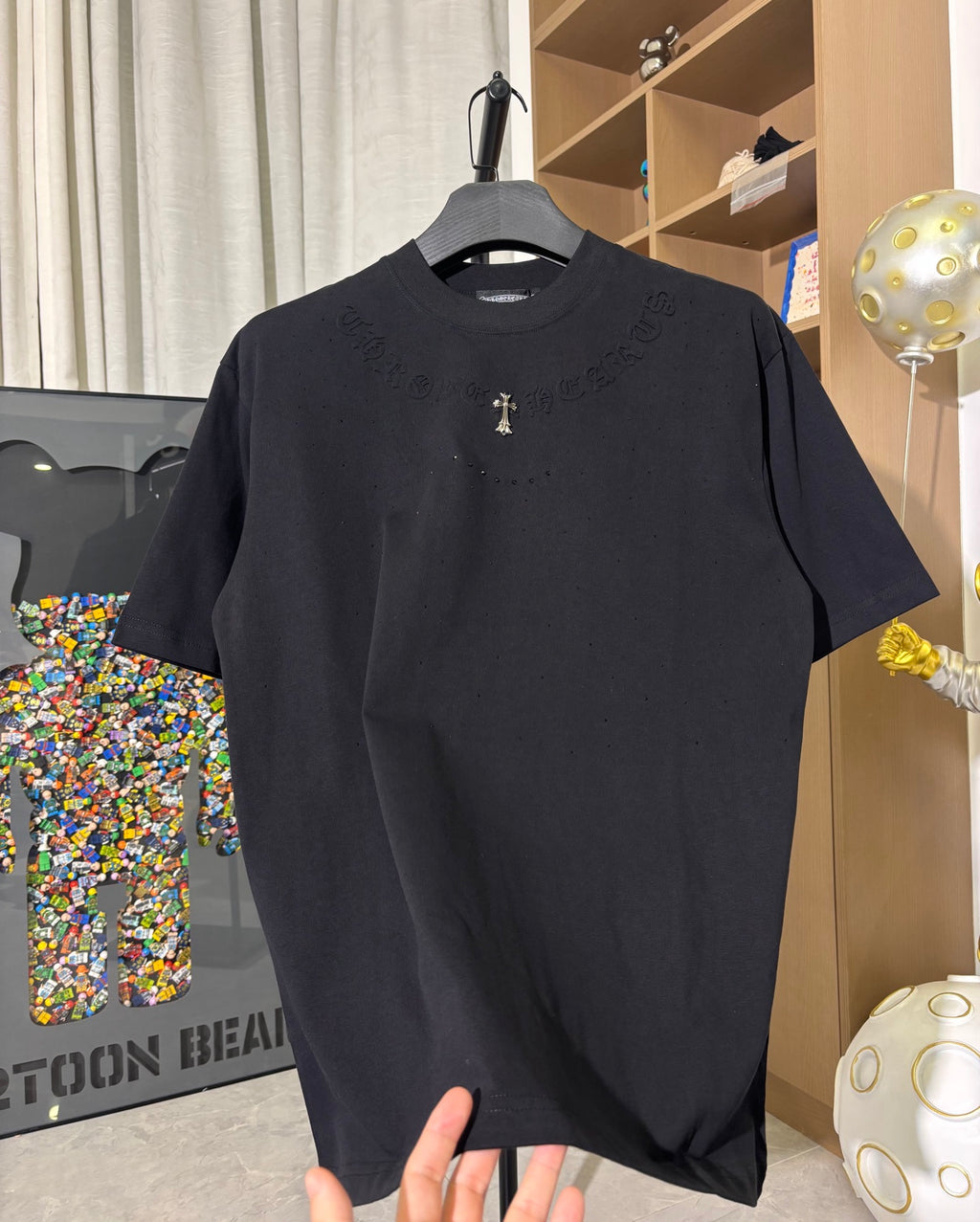 Black crew-neck short-sleeve T-shirt with gold cross emblem on chest