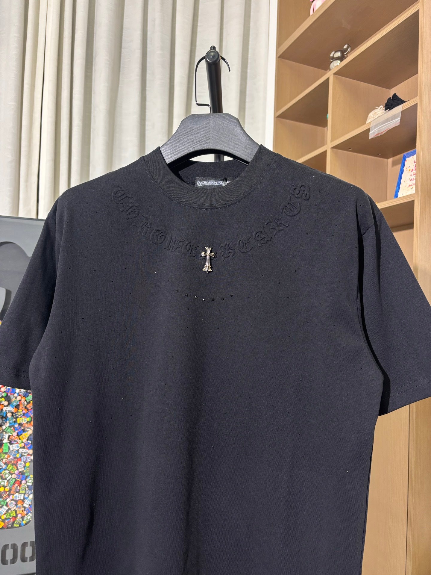 Black crew-neck T-shirt with raised side text and small gold cross emblem