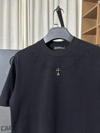 Black crew-neck T-shirt with subtle raised text pattern and small gold cross logo