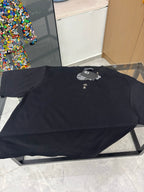 Black crew-neck T-shirt lying flat, gold cross emblem and raised logo detail