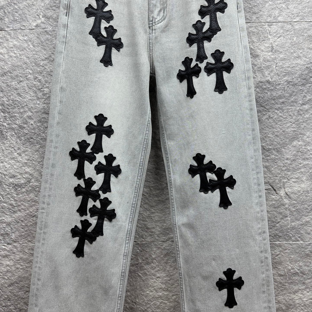 Light wash denim pants with scattered black cross appliqués along the legs