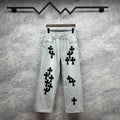 Light wash denim pants with black cross appliqués, button fly, belt loops