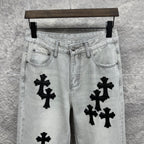 Light wash denim pants waistband with belt loops and black cross appliqués on front